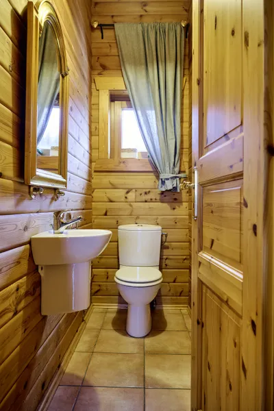 Blick in das Badezimmer mit Toilette, Waschbecken, Spiegel und kleinem Fenster.