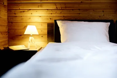 Nahaufnahme der linken Seite eines Bettes mit gemütlichem Licht eine Lampe auf dem Nachttisch.