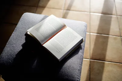 Aufgeschlagenes Buch auf einem Hocker im Wohnzimmer.