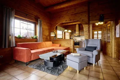 Gemütliches Wohnzimmer mit Sofa, Sessel und großem Fenster.