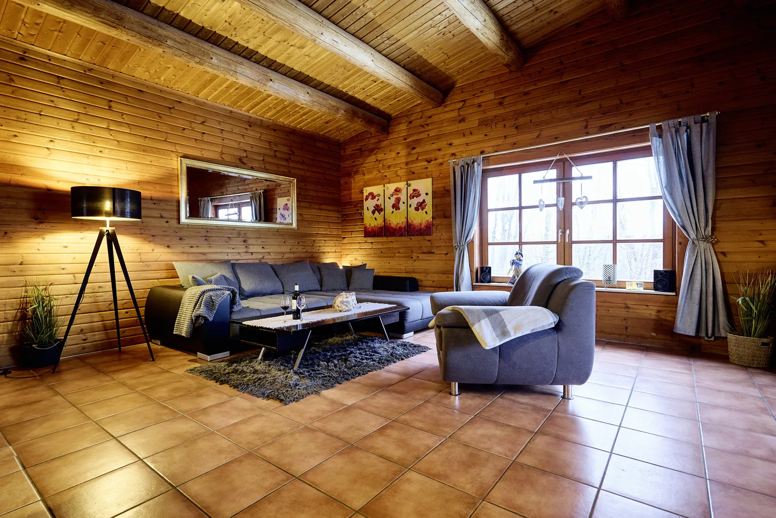 Helles Wohnzimmer mit einem Sofa, Sessel und großem Fenster.