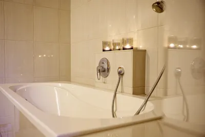 Helles Badezimmer mit Badewanne im Kerzenschein.