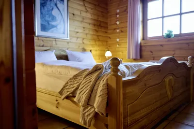 Blick in ein Schlafzimmer mit Doppelbett und Fenster und fokussiertem Pullover im Vordergrund.
