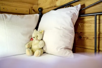 Nahaufnahme eines Bettes mit Kissen und einem Teddybär.