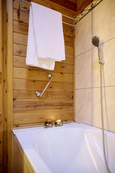 Gemütliche Badewanne mit Duschkopf und Handtuchhalterung.