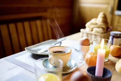 Nahaufnahme des gedeckten Frühstückstisches mit einer Tasse Kaffee im Fokus.